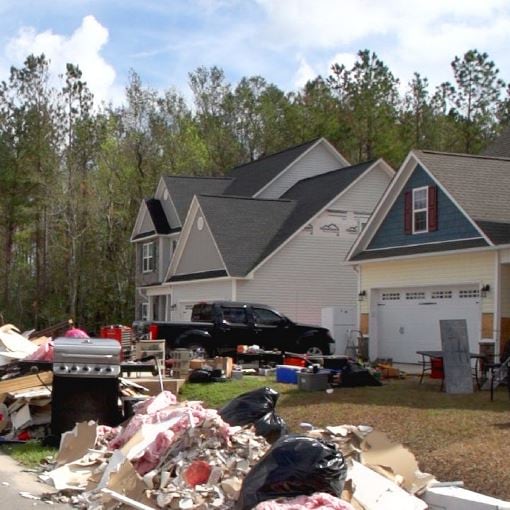 Storm damaged homes with piles of unusable items on street