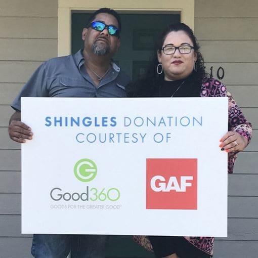 Homeowners holding sign sharing their roof shingles were donated by GAF 