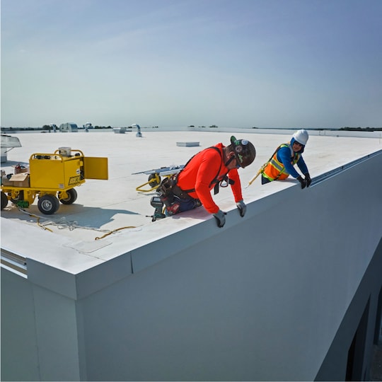 Contractor rolling GAF vapor barrier on a commercial building.