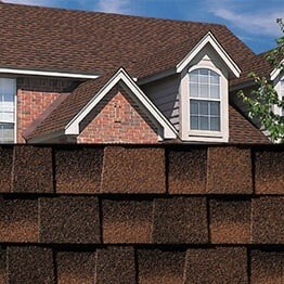 Timberline HDZ hickory shingle sample with roof image of shingles on a brick home.