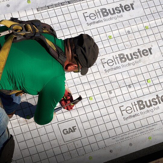 Shaded image of a GAF roofer installing a GAF roof deck protection underlayment sheet