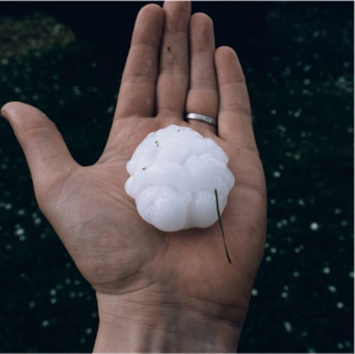 Hand holding a large piece of hail.