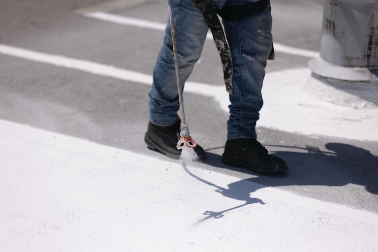 A contractor coating a flat roof with GAF Unisil Silicone.