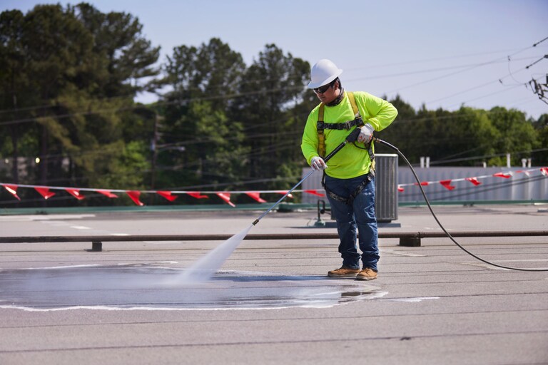 A contractor power washing a flat roof using GAf's Cleaning Concentrate.