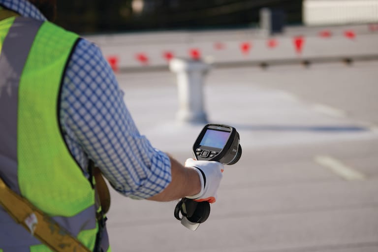 GAF contractor performing moisture scan with instrument on a flat roof