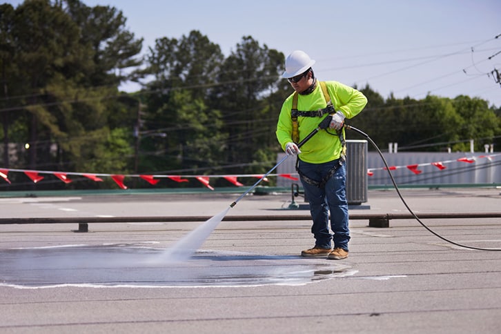 A contractor power washing a flat roof using GAf's Cleaning Concentrate