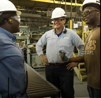 Smiling GAF employees in roofing manufacturing plant