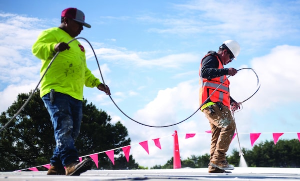 Commercial roofing contractors spraying roof coating products