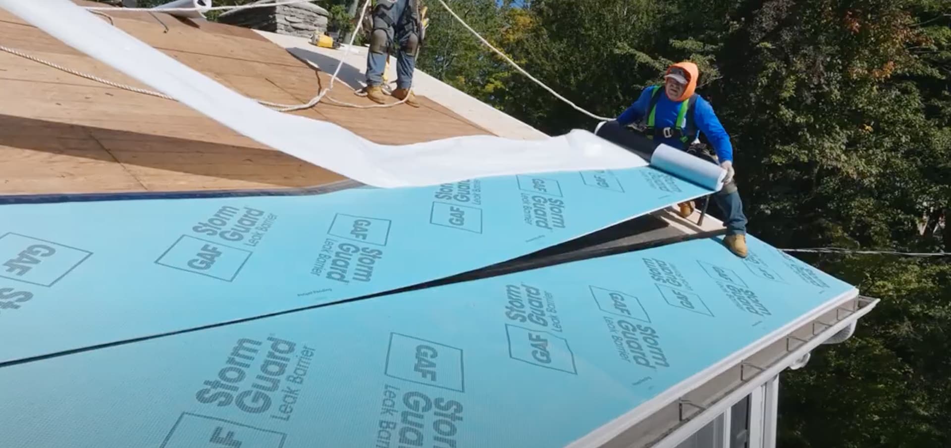 Roofer installing GAF underlayment on a residential roof with GAF Timberline shingles