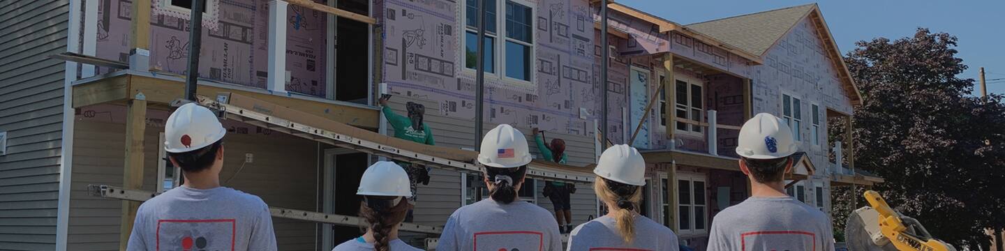 GAF roofing employees looking at a new home they are helping to build in their community.