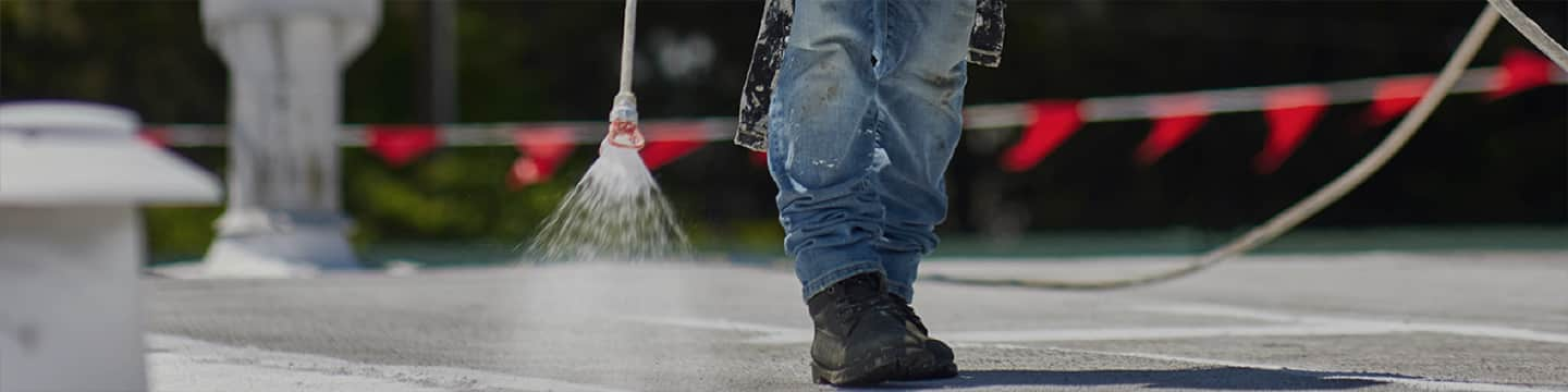 A GAF contractor spraying an acrylic coating on an asphalt roof. 