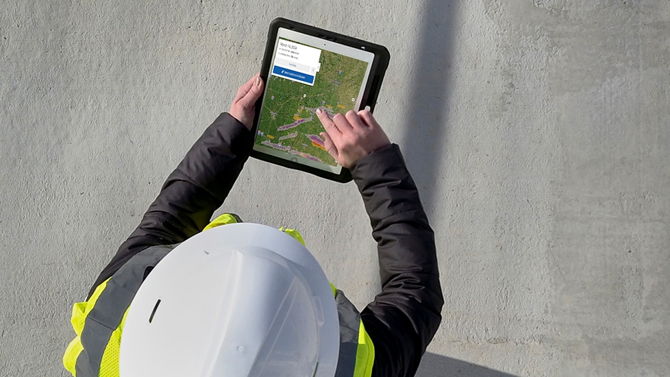 Roofing contractor holding tablet using interactive hail map from by GAF WeatherHub