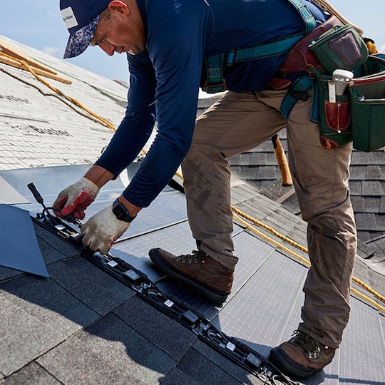 Roofing contractor installing Timberline solar roof shingles on roof