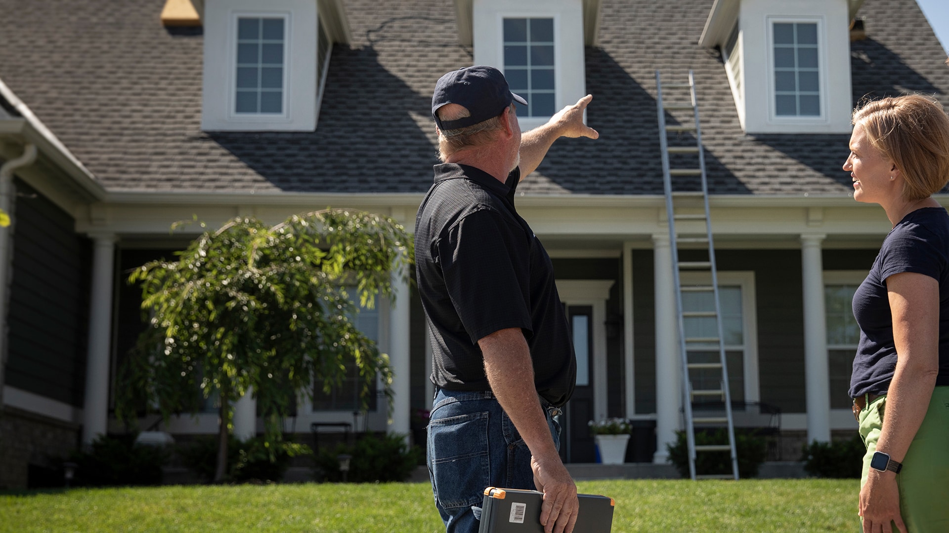 Roofing Contractor working with a homeowner pointing at a roof
