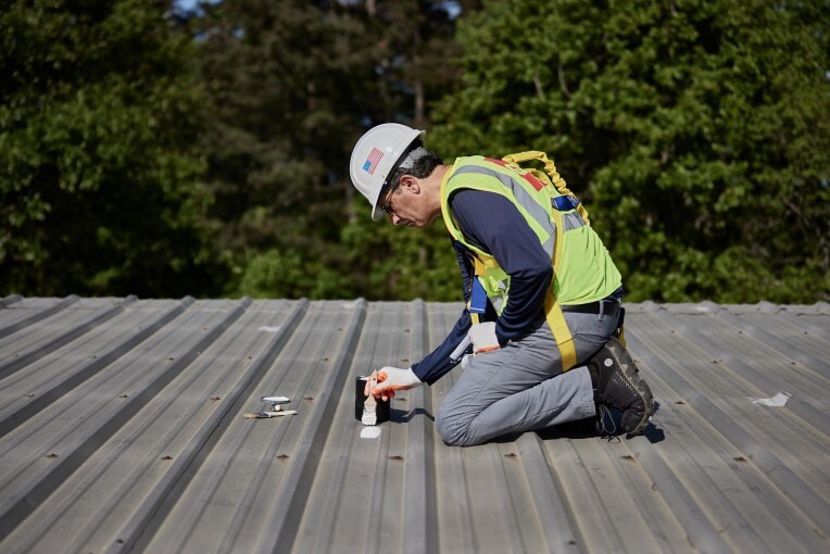 Contractor with brush on metal roof