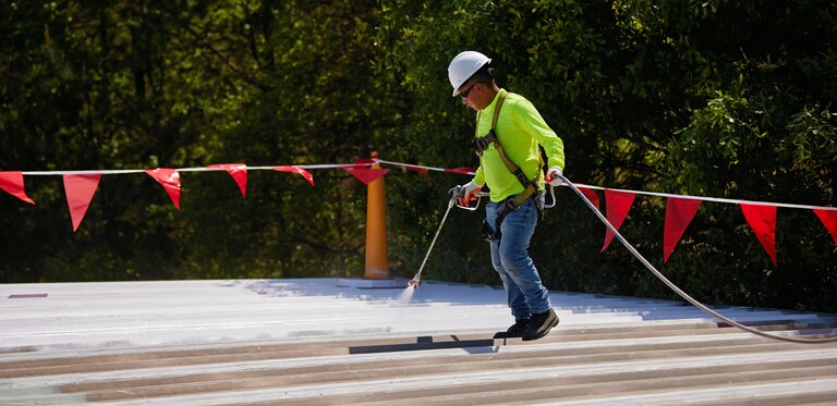 Roofing contractor spraying coating on flat roof